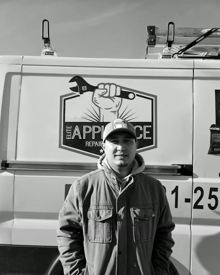 Brahian Perez, owner of Elite Appliance, standing in front of the company van beside the fist-and-wrench badge